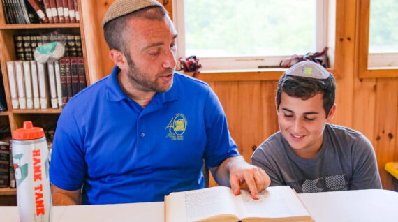 A staff member and camper reading together.