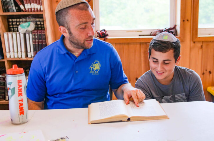 A Camp Nesher staff member and a camper reading the Torah.